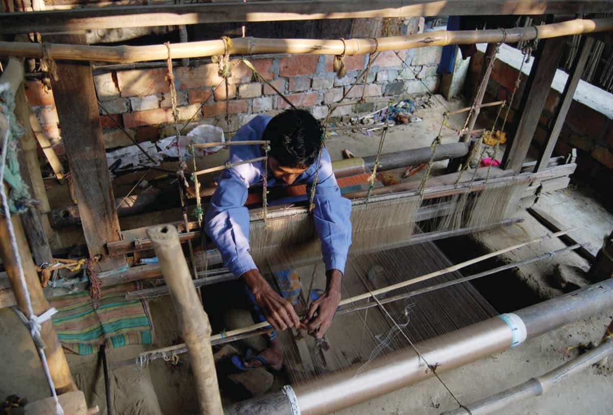 Chandabrati-man-adjusting-loom-overhead Adjusting a loom at Chhandabrati Weavers