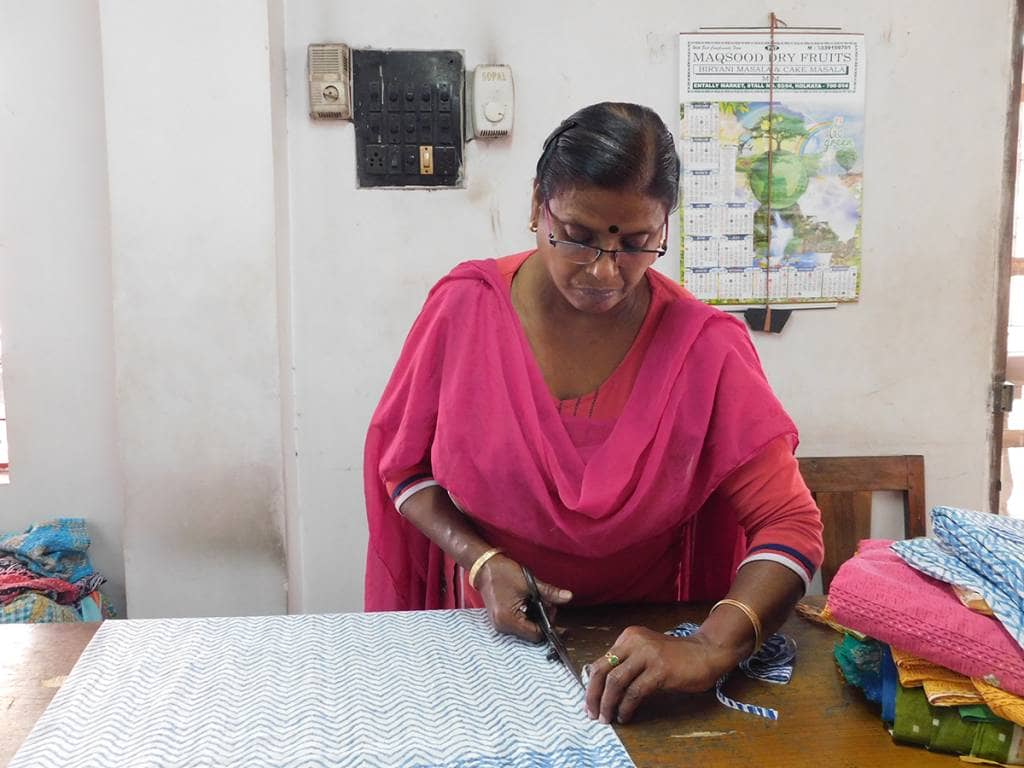 Woman cutting out fabric wearing a pink salwar